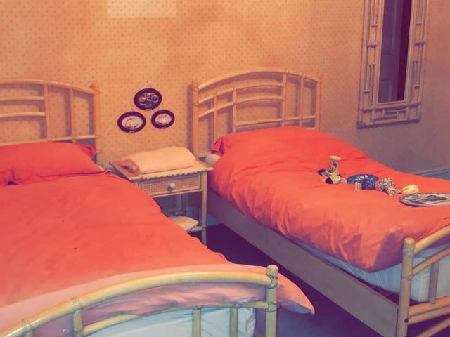 A double bed and twin bed lay empty. Eerily, they're both made up perfectly.