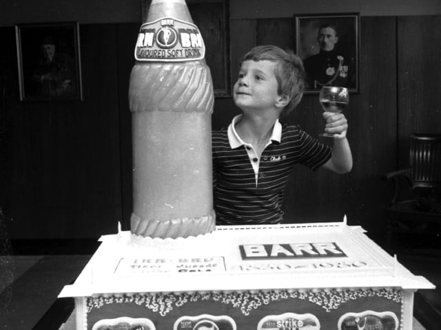Graham Barr raises a glass beside a cake to celebrate the 150th anniversary of the Irn-Bru company in Glasgow in August 1980.