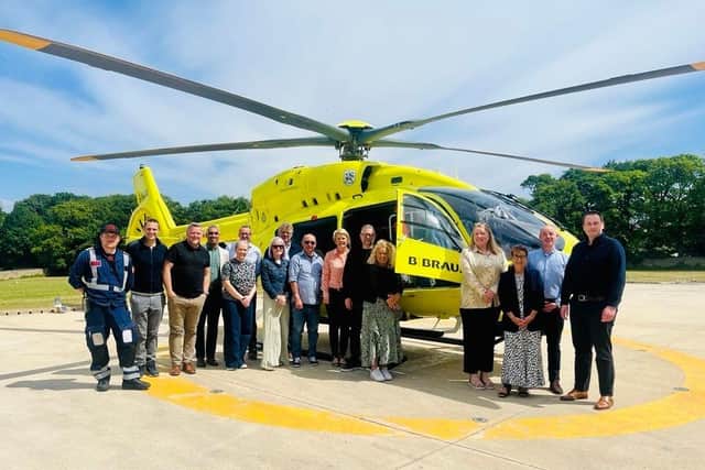 B. Braun staff stood in front of a Yorkshire Air Ambulance helicopter.