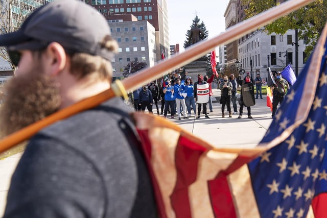 A Trump supporter demonstrating the election results holds an American flag while facing off with counter protesters at the State Capitol in Lansing, Mich (AP Photo/David Goldman)