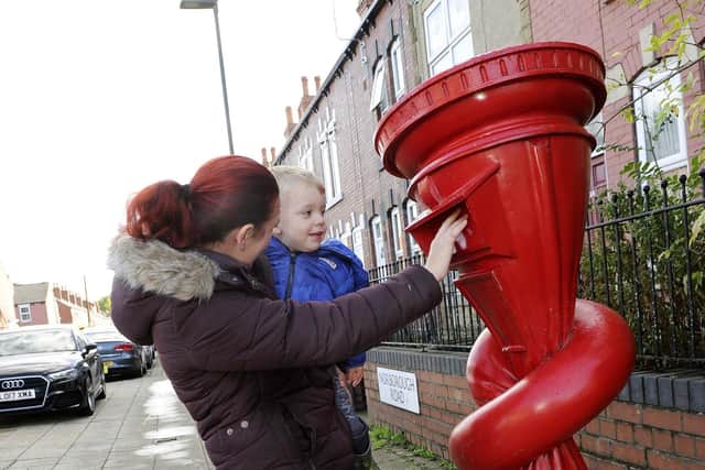 Denise Vickers and her son Riley have a close look at the knotted postbox sculpture Alphabetti Spaghetti by artist Alex Chinneck which appeared on Norborough Road, Tinsley in September 2019