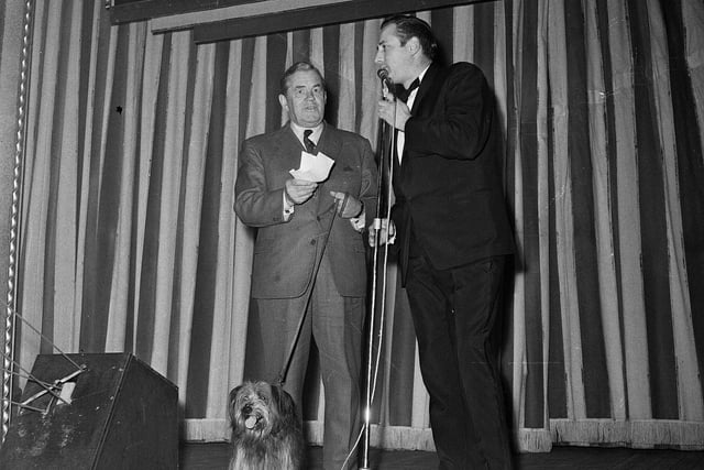 Chief Constable Merrilees is accompanied by the dog that played Bobby in the recently-released Disney film while receiving a charity cheque from the manager of the Mecca Empire Bingo Club in October 1964.