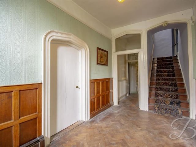 The home has two dominant hallways which you can access from the front. This one has wood panels.