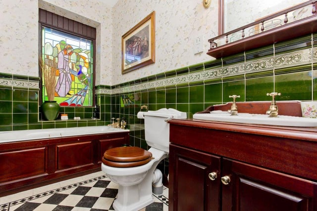 The ground floor bathroom features a bespoke stained-glass window and vanity storage.