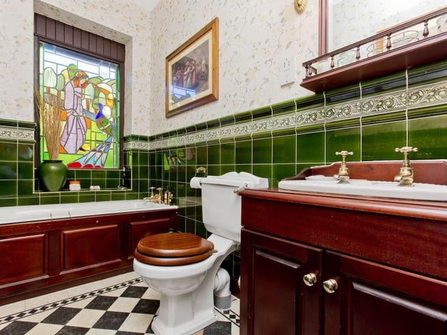 The ground floor bathroom features a bespoke stained-glass window and vanity storage.