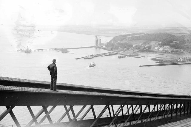 A painter walking down the centre girder of the Forth Bridge looks over to the Forth Road Bridge under construction in 1962.