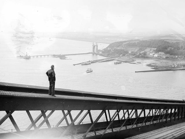 A painter walking down the centre girder of the Forth Bridge looks over to the Forth Road Bridge under construction in 1962.