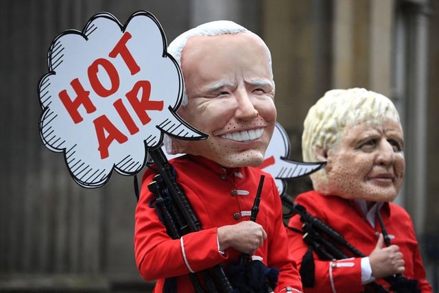 Oxfam activists dressed as a Scottish pipe band and representing US President Joe Biden and British Prime Minister Boris Johnson take part in their "Big Heads" protest stunt at the Royal Exchange Square in Glasgow (Getty Images)