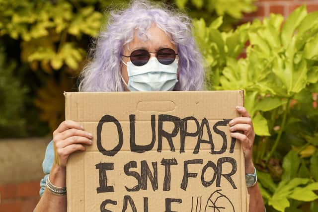 A woman holding up a placard in support of Department of Archaeology.