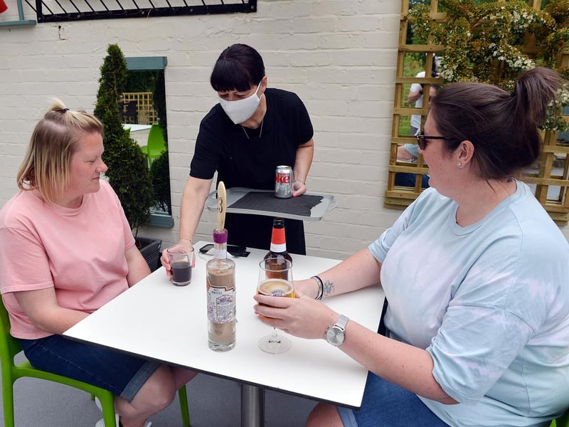 Customers Stacey Wilkinson and Lucy Smith are served drinks in the sunshine by Cakefield Cakes employee Wendy.