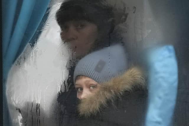 A woman and child peer out of the window of a bus as they leave Sievierodonetsk, the Luhansk region, in eastern Ukraine, Thursday, Feb. 24, 2022." (AP Photo/Vadim Ghirda)