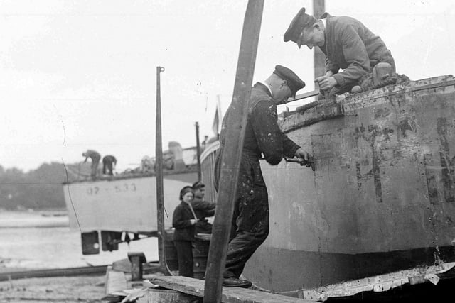 Men and women working on landing craft

