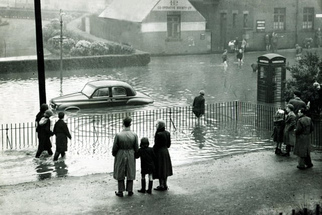 Passers-by pause to look at a car stranded in the flood water at Firth Park terminus - the car belonged to the Deputy Lord Mayor, Coun Oliver S Holmes, August 21, 1954
