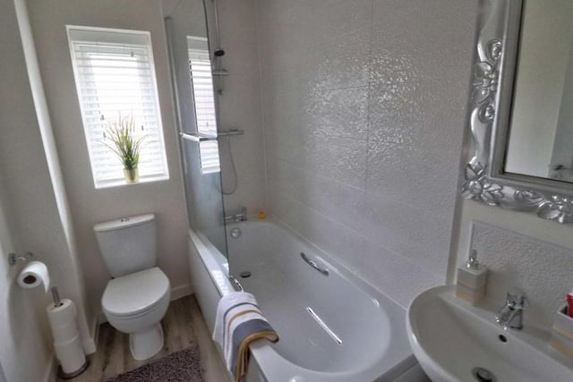 A three-piece white suite, comprising bath, wash hand basin and low-flush WC, makes up the family bathroom on the first floor of the Kernel Way house. Again, the wet areas are tiled, while the wood-effect floor is cushioned.