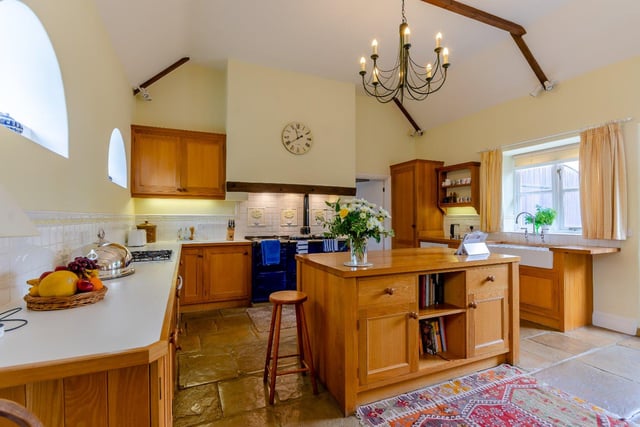 The spacious kitchen features a flagstone floor, stable arched windows, a range of high and low level kitchen cupboards and a four oven Aga, plus a central island which serves as a breakfast bar.