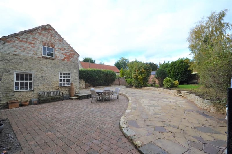 Large private walled garden  with various patio seating areas and a lawned garden with well stocked borders and raised flower beds.