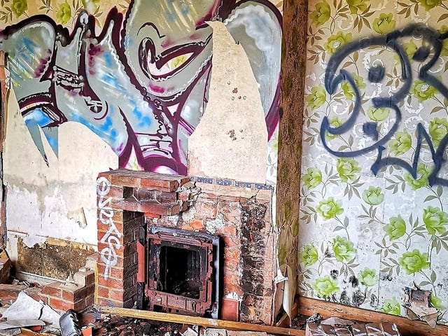 Brickwork around an old fireplace has been pulled from the wall.