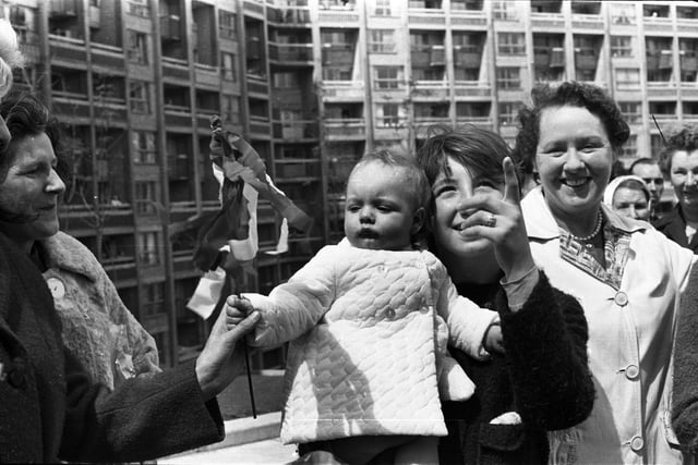 A toddler waves a flag at the Queen Mother at Sheffield's Hyde Park flats during her visit on June 23, 1966.