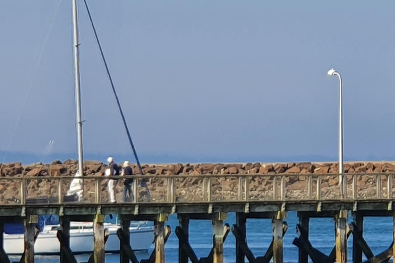People watch on the jetty as boats pass by, presumably to make their way to the open ocean on a lovely day!