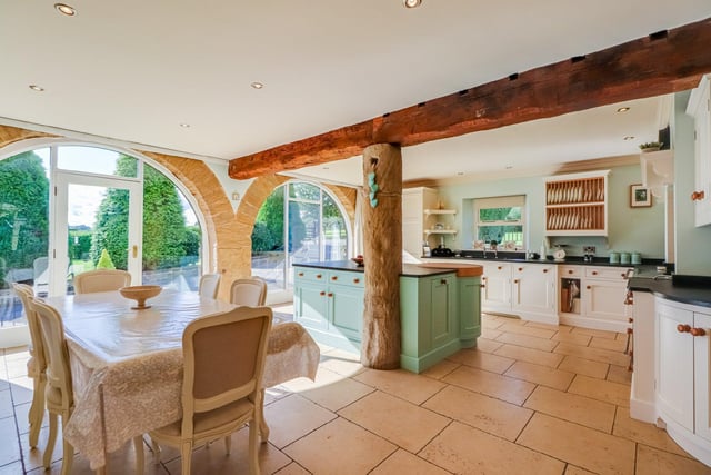 This bright room is bathed in plenty of light from two arched barn style windows and boasts a bespoke range of painted wall and base units with dark granite worktops, a Falcon Range style cooker, and integrated appliances.