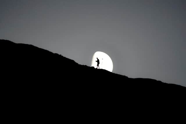 A photographer is pictured silhouetted against the moon in this shot capured in the Peak District at Edale, which went viral after being shared online (pic: Stuart Coltman / SWNS)