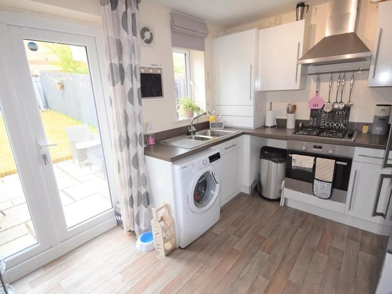 Breakfast kitchen has a range of modern high gloss units with contrasting worktops including stainless steel oven and hob with chimney style hood over, stainless steel sink with mixer tap and drainer, plumbing for a washing machine, space for fridge freezer, concealed Ideal Logic combi gas boiler, UPVC double glazed window, breakfast bar and UPVC double glazed patio doors.