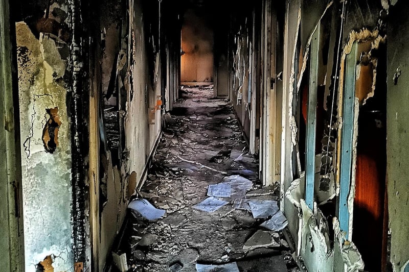 An internal corridor damaged by fire and vandals.