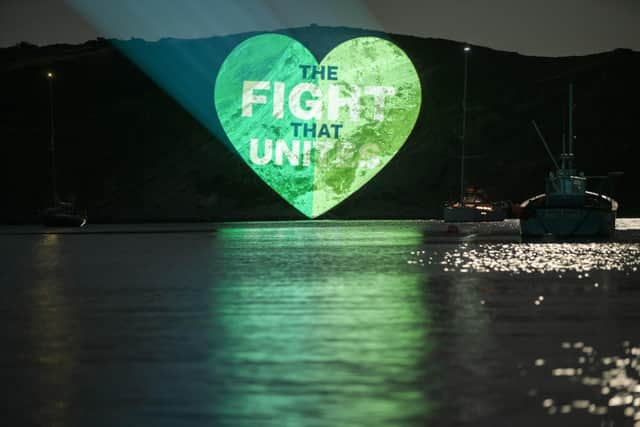 EDITORIAL USE ONLY 
General views as 'The Fight That Unites' logo is projected onto a cliff side at Lulworth Cove in Dorset for The Great Big Green Week by The Climate Coalition, which aims to celebrate the support for climate action, to protect nature and the environment, across the UK. Issue date: Tuesday September 21, 2021. PA Photo. Photo credit should read: Nigel Swan/PA Wire
