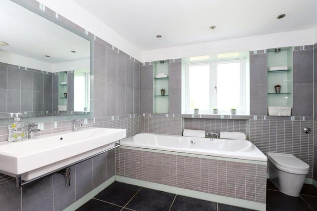 This large, bright bathroom is located right at the top of the stairs and is likely shared between those who use bedrooms without en-suites. It's got a large sink, bath and shower and has a sleek, modern finish.