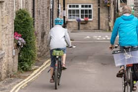 Two cyclists travel down a street in Bradwell village, Hope Valley