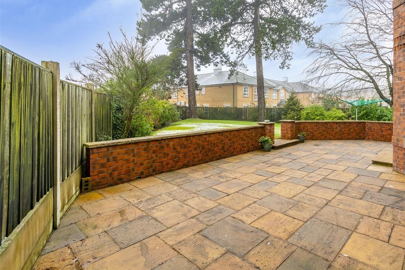 The rear garden features a paved patio seating area with wall surround.