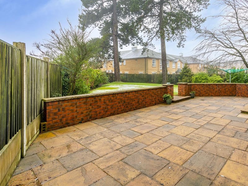 The rear garden features a paved patio seating area with wall surround.
