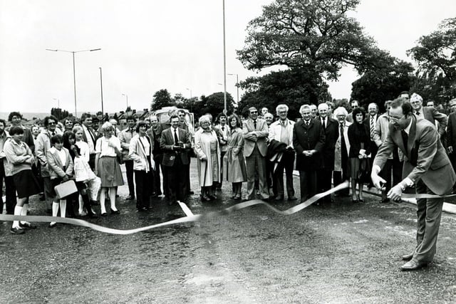 Coun Norman West, Chairman of the Highways Committee, cuts the tape to officially open the new Norton bypass, watched by councillors, officials and members of the public, June 28, 1982