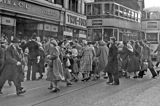 Shoppers on Haymarket, in Sheffield city centre, with True Form Boot Co and F.W. Woolworth and Co visible, and trams in the background, in 1953