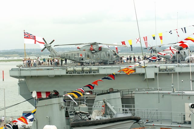 HMS Illustrious towers above other ships and her white ensign flies on the stern deck as crowds tour the ship. Picture: Malcolm Wells 053125-59