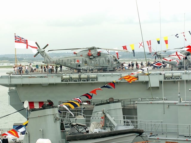 HMS Illustrious towers above other ships and her white ensign flies on the stern deck as crowds tour the ship. Picture: Malcolm Wells 053125-59