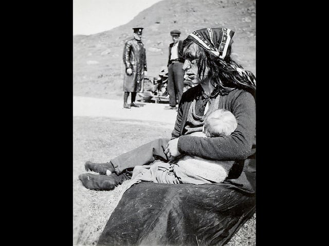 A travelling woman rests at side of road as policeman looks on. Shennan started work in the Highlands in 1925 when he took up a new post as inspector for the Royal Scottish Society for the Prevention of Cruelty to Children.