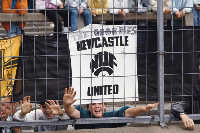 Newcastle United fans hang their flags to the safety fence surrounding the pitch before a First Division match against Liverpool at St James' Park.