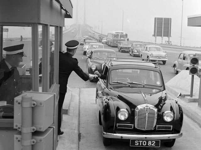 One of the first drivers to cross the bridge pays the toll in 1964.