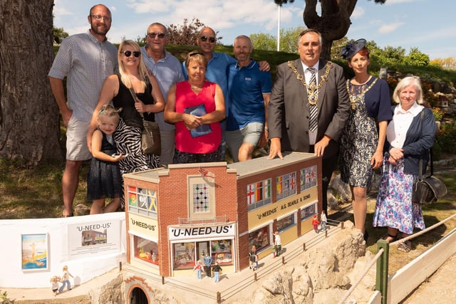 Dean Wilson, Ian Morson, Mark Wilson, Stephen Searle, Mayor of Portsmouth Councillor David Fuller, Mrs Leza Tremorin, Sandra Haggen at the unveiling of a model of the U-Need-Us shop at Southsea Model Village in May 2019.
