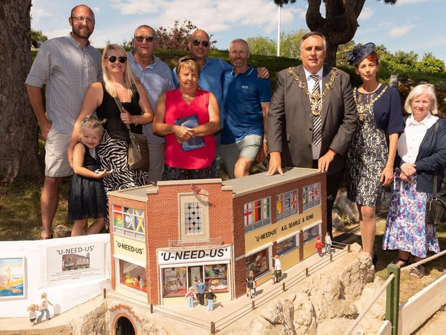 Dean Wilson, Ian Morson, Mark Wilson, Stephen Searle, Mayor of Portsmouth Councillor David Fuller, Mrs Leza Tremorin, Sandra Haggen at the unveiling of a model of the U-Need-Us shop at Southsea Model Village in May 2019.