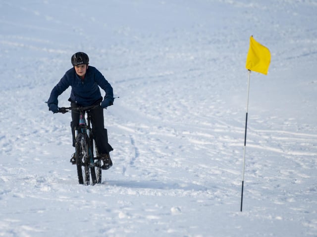 A mountain biker rides across a green at The Braids Golf Course.