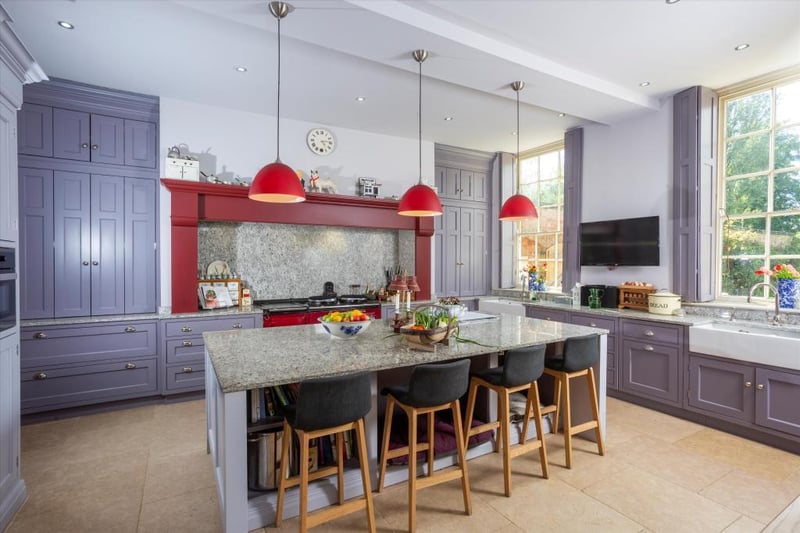 The kitchen has granite work surfaces, a limestone floor, double Belfast sink, painted floor and wall-mounted units with built-in modern appliances and a useful utility/garden room leading immediately off it.