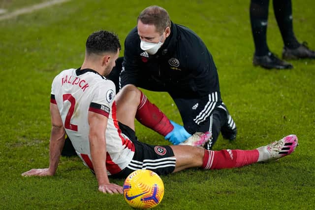 Sheffield United's George Baldock receives treatment after picking up an injury during the Premier League football match between Sheffield United and West Bromwich Albion at Bramall Lane (Photo by TIM KEETON/POOL/AFP via Getty Images)
