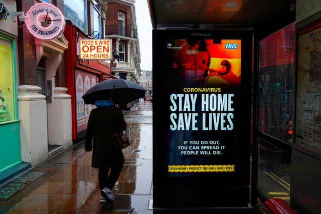 A pedestrians walks past NHS signage promoting "Stay Home, Save Lives" on a bus shelter in London on January 14, 2021 during Britain's third coronavirus lockdown. (Photo by Niklas HALLE'N / AFP) (Photo by NIKLAS HALLE'N/AFP via Getty Images)