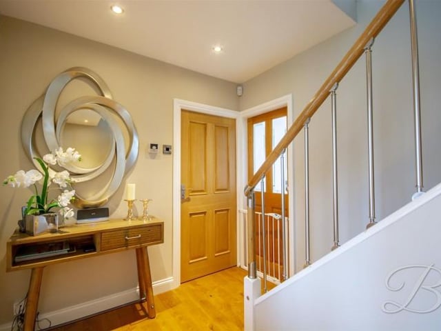 An inviting reception space, featuring wood flooring, central heating radiator and stairs rising to the first floor accommodation.