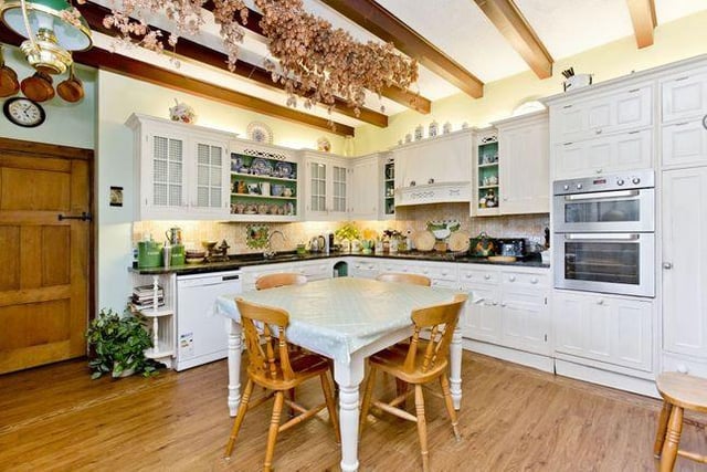 The dining kitchen is fitted with a large range of country-styled bespoke cabinets and is framed by granite worktops