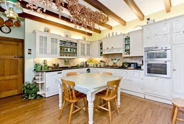 The dining kitchen is fitted with a large range of country-styled bespoke cabinets and is framed by granite worktops