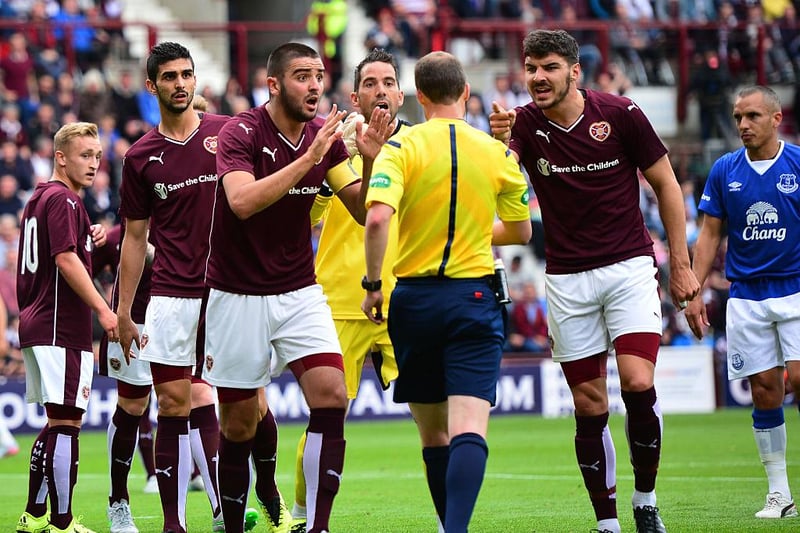 Hearts players, led by captain Alim Ozturk and Callum Paterson, protest against the award of a penalty.
