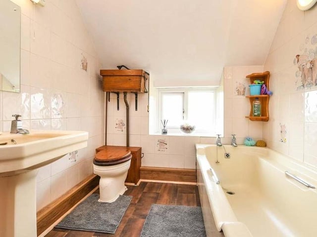 At the back of the house, on the first floor, is this family bathroom. A three-piece suite consists of a panelled bath, wash hand basin, a pull-chain WC, partly tiled walls and a uPVC double-glazed window.